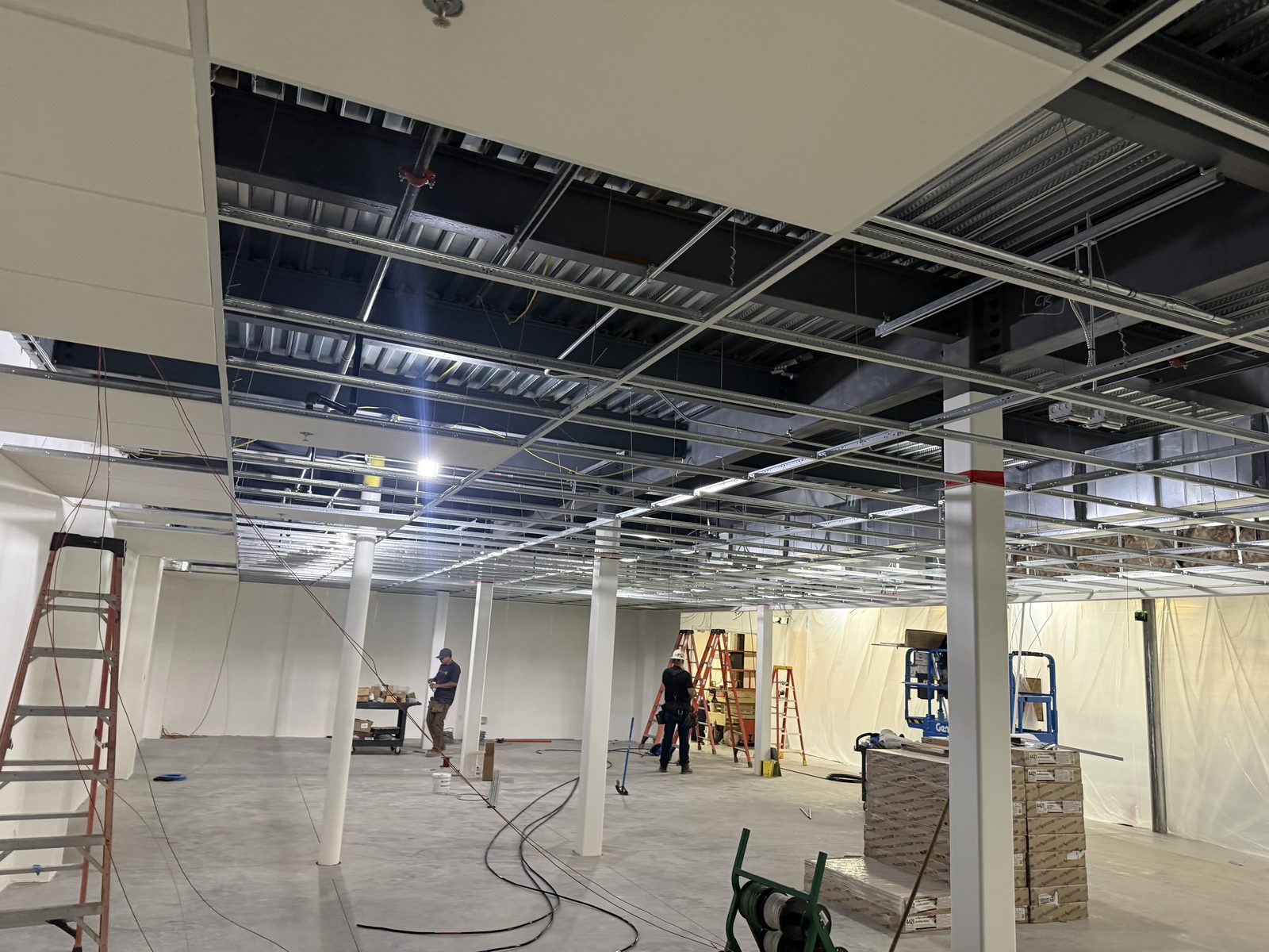 Suspended ceiling grid being framed below overhead electrical in a commercial interior