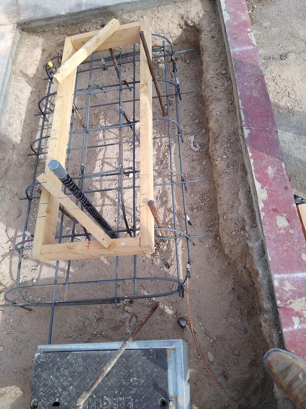 Kiosk foundation rebar with an anchor-bolt template, conduit stub and grounding conductor set before the pour